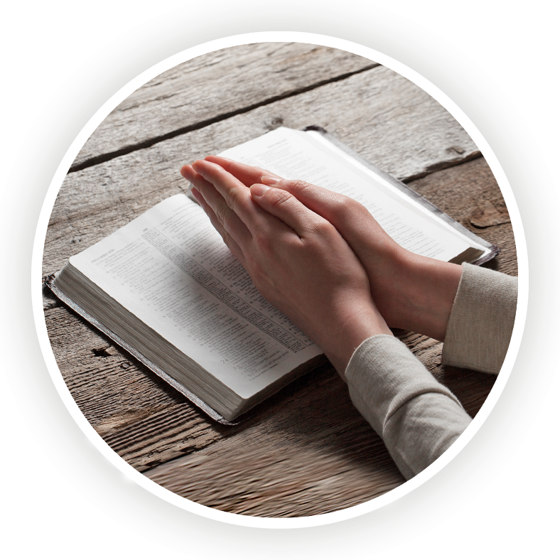 Praying hands over an open bible